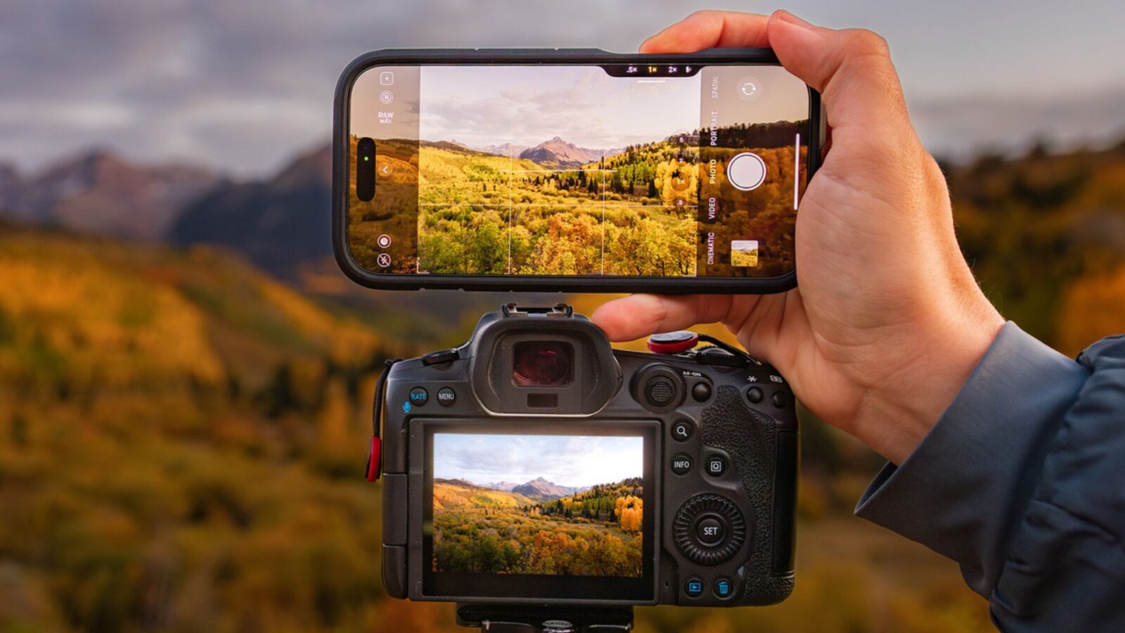 pessoa segurando um iphone 16 pro max em cima de uma câmera profissional tirando foto da natureza.
